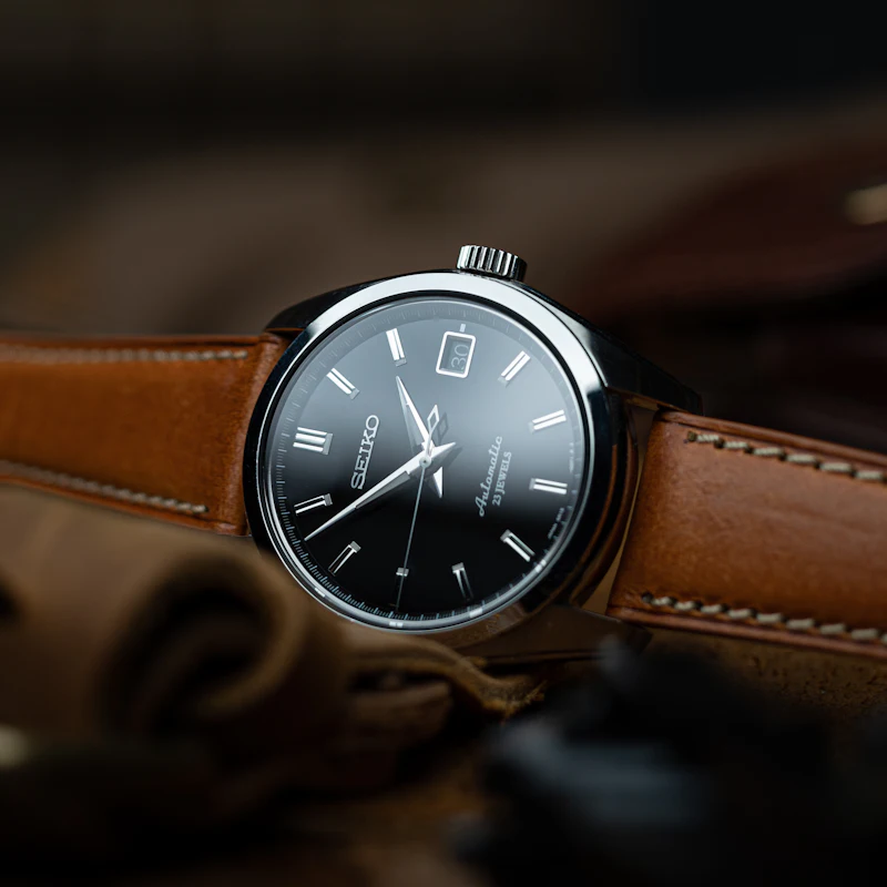 Montre à cadran noir montée sur un bracelet en cuir cognac