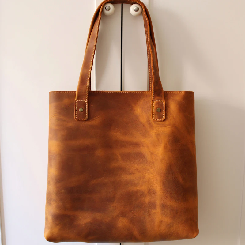 Cabas en cuir cognac suspendu à des patères